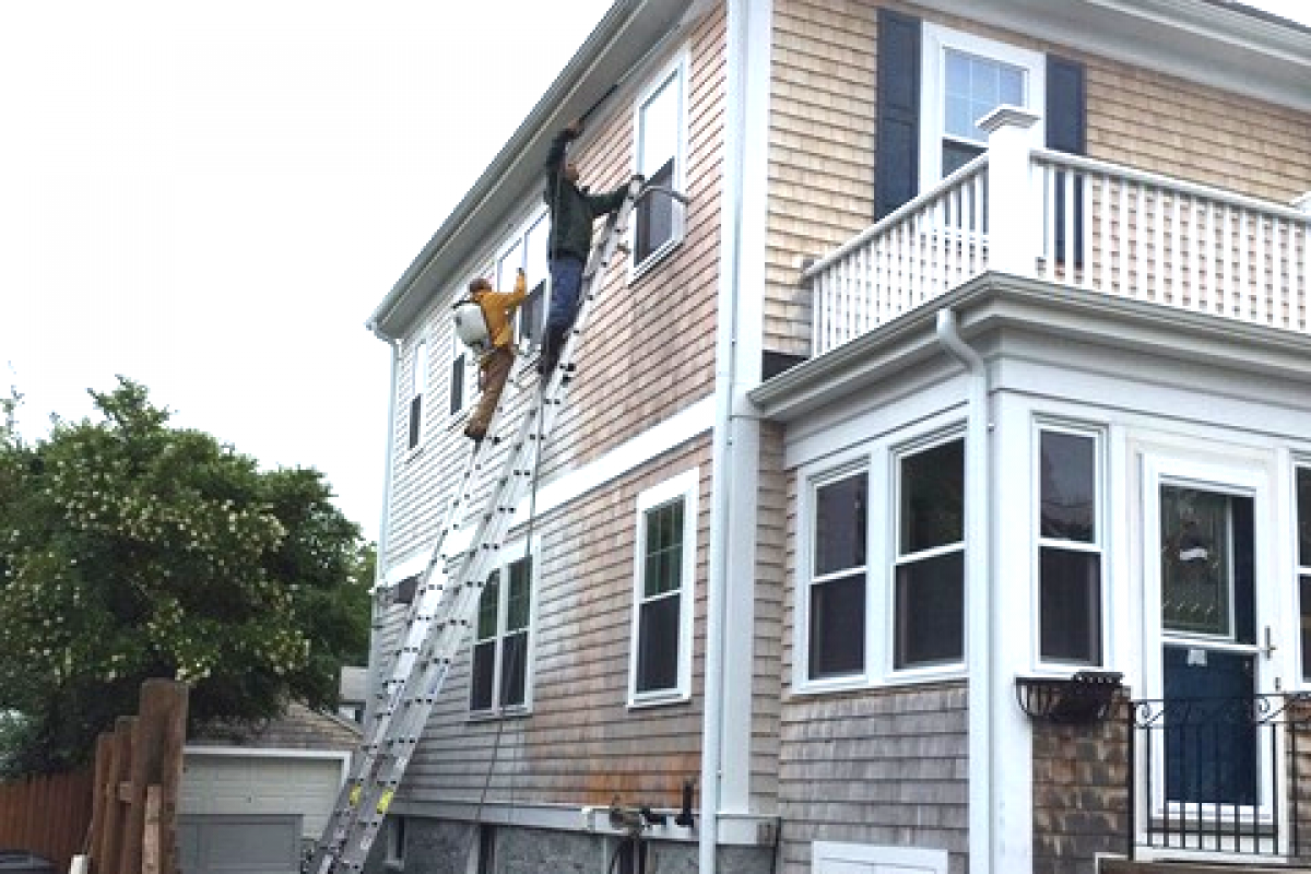 A photo of Liberty Painting staff power-washing the side of a beautiful home in Scituate.