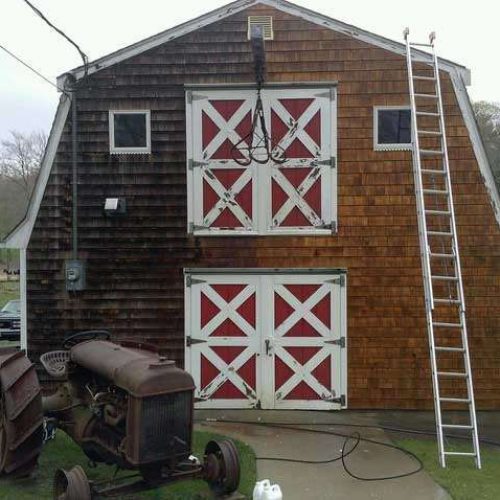 Large barn halfway through a power washing . The right side is clean and the left side still dirty.