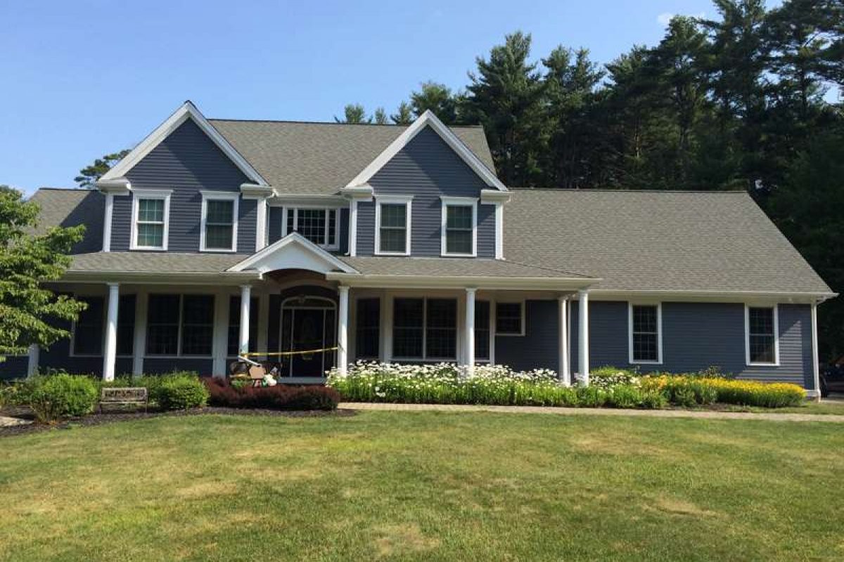 A large colonial house professionally painted blue with white accents, painted by Liberty Painting and Siding.