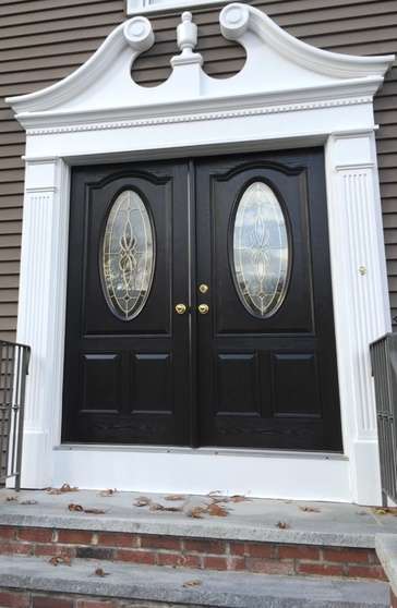 A completed front door replacement project featuring double black doors with golden knobs and oval windows