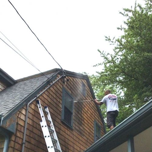 A photo of a Liberty Painting staff member power-washing the side of a beautiful home in Halifax.