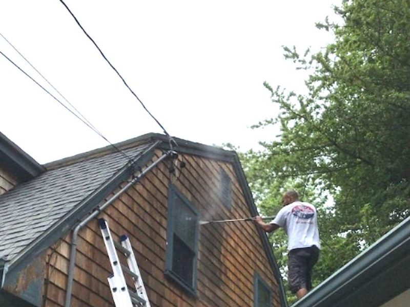 A photo of a Liberty Painting staff member power-washing the side of a beautiful home in Halifax.