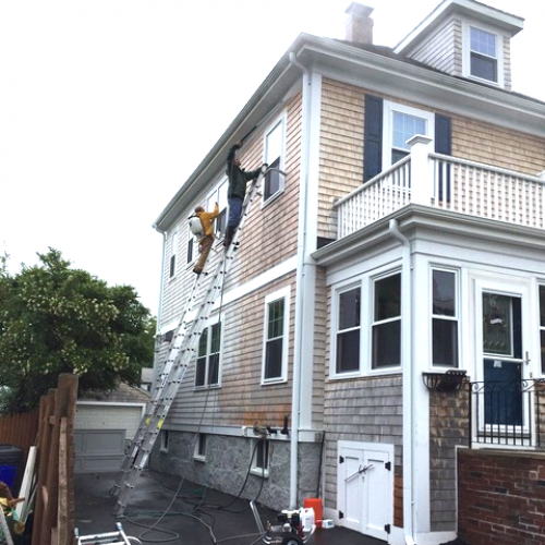 A photo of Liberty Painting staff power-washing the side of a beautiful home in Scituate.