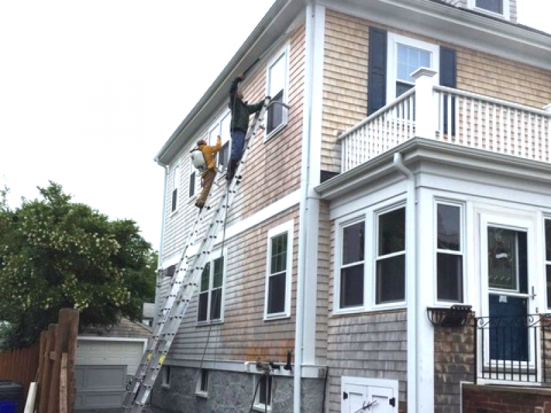 A photo of Liberty Painting staff power-washing the side of a beautiful home in Scituate.