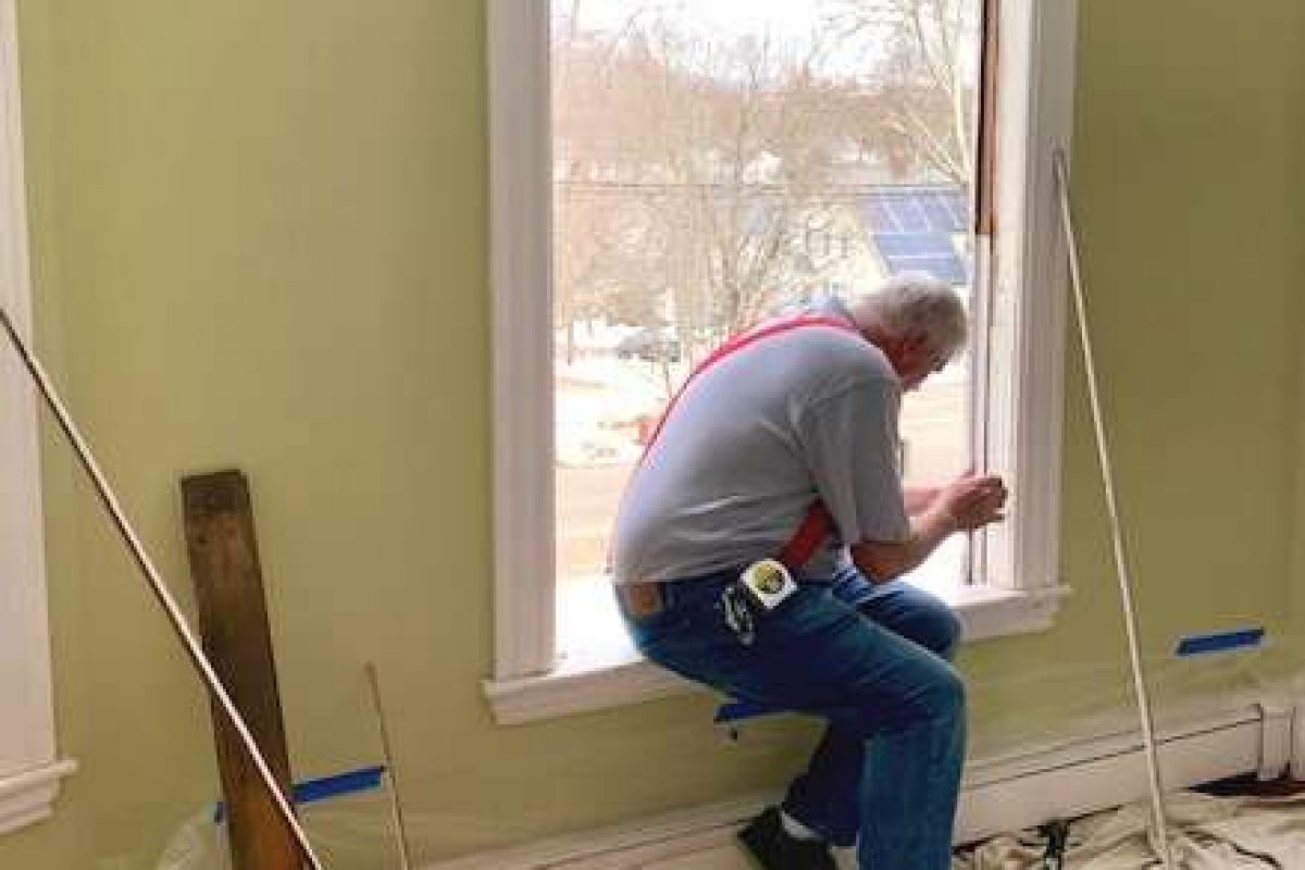 A photo showing a member of the Liberty Painting team working to install a new window.