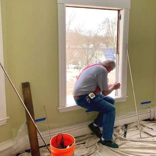 A photo showing a member of the Liberty Painting team working to install a new window.