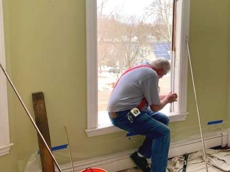 A photo showing a member of the Liberty Painting team working to install a new window.