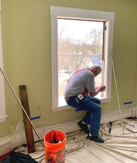 A photo showing a member of the Liberty Painting team working to install a new window.